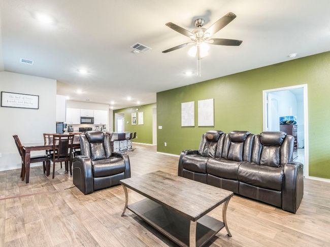 Living room with baseboards, visible vents, light wood-style floors, and a ceiling fan | Image 14