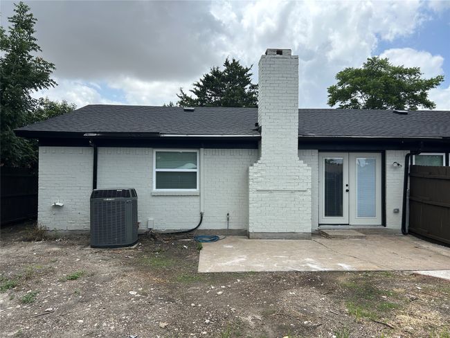 Rear view of house featuring central AC unit, french doors, brick siding, a chimney, and a shingled roof | Image 5