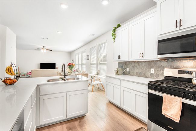 Kitchen featuring stainless steel appliances, light countertops, a sink, and light wood-style flooring | Image 11