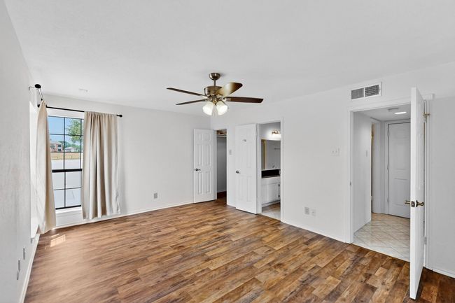 Unfurnished bedroom with wood finished floors, ensuite bathroom, a ceiling fan, and baseboards | Image 27