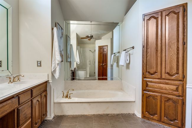 Full bath featuring vanity, a bath, a shower stall, tile patterned floors, and a ceiling fan | Image 22