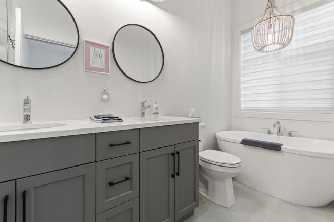 Bathroom with double vanity, a freestanding bath, a chandelier, toilet, and tile patterned flooring | Image 20