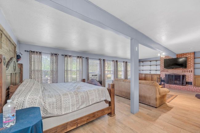 Bedroom with a fireplace, wood finished floors, and cooling unit | Image 17