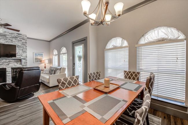 Dining space featuring wood finished floors, crown molding, a fireplace, ceiling fan, and a chandelier | Image 6