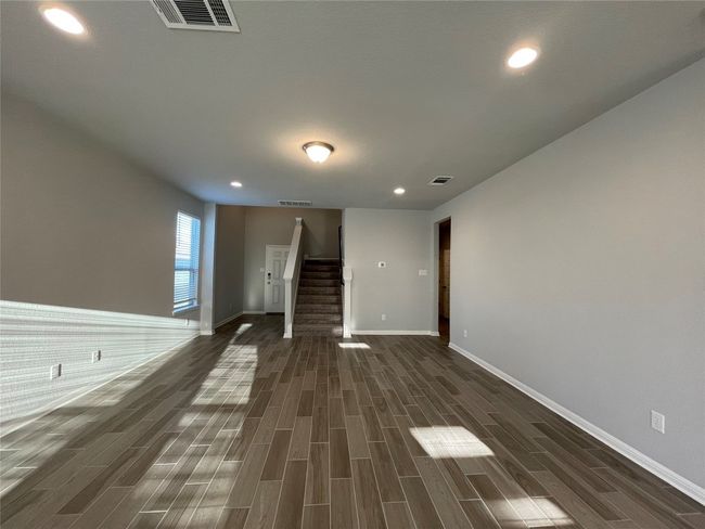 Empty room with stairs, dark wood-style floors, and recessed lighting | Image 8