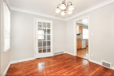 Unfurnished dining area featuring hardwood / wood-style flooring and a notable chandelier | Image 3