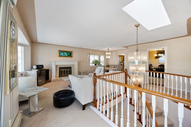 Corridor featuring a skylight, a notable chandelier, an upstairs landing, and light colored carpet | Image 14
