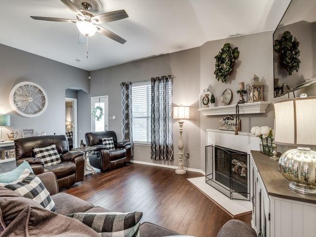 Living area with a tile fireplace, ceiling fan, wood finished floors, arched walkways, and baseboards | Image 9