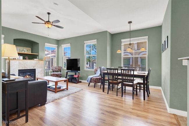 Living room with wood like finished floors, a tiled fireplace, a ceiling fan, and baseboards | Image 8