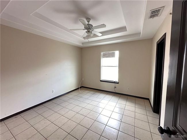Tiled spare room with a raised ceiling and ceiling fan | Image 5