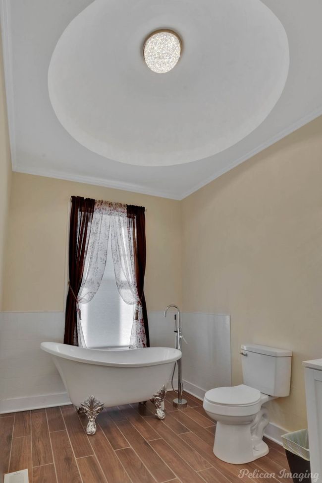Full bathroom with a freestanding bath, wood finished floors, crown molding, and a tray ceiling | Image 15