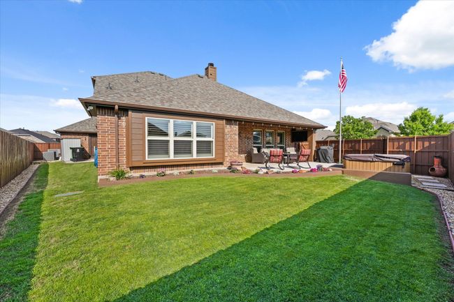 Rear view of property with a chimney, a fenced backyard, a hot tub, a patio, and brick siding | Image 37