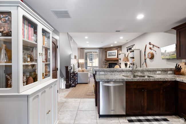 Kitchen with dark brown cabinets, a sink, dishwasher, a peninsula, and visible vents | Image 12
