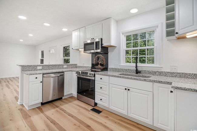 Kitchen featuring a peninsula, stainless steel GE appliances, white cabinetry, and recessed LED lighting. The new WiFi equipped GE stainless steel range features an Air Fryer. It also offers both regular baking and convection baking. | Image 10