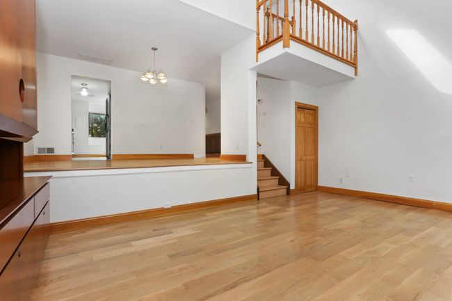 Unfurnished living room featuring light wood-style floors, stairs, a chandelier, and baseboards | Image 19