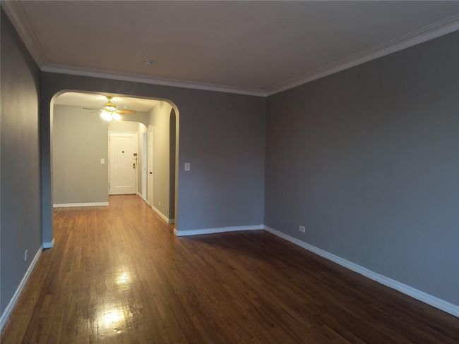 Empty room with ceiling fan, baseboards, ornamental molding, dark wood-style floors, and arched walkways | Image 16