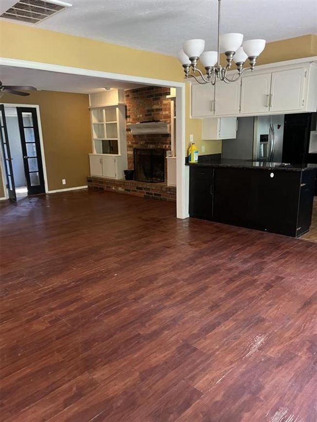 Unfurnished living room with dark wood-style floors, a brick fireplace, a chandelier, and ceiling fan | Image 31