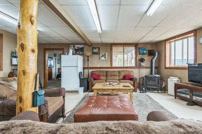 Living area with a wood stove, a paneled ceiling, and plenty of natural light | Image 37
