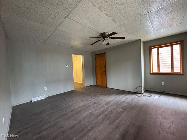 Unfurnished room with dark wood-style floors, ceiling fan, a drop ceiling, and visible vents | Image 8