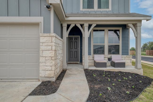Doorway to property with stone siding, covered porch, an attached garage, and board and batten siding | Image 5