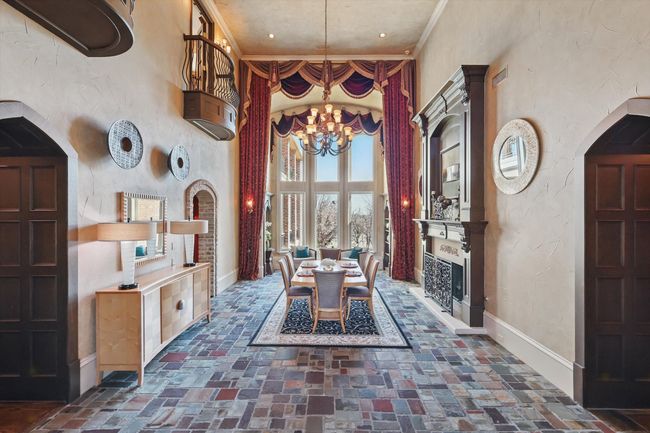This grand entry can be formal dining or living space and is complete with floor to ceiling Anderson windows, a stately fireplace, and a movable book case for ease of moving furniture into the primary bedroom. | Image 7
