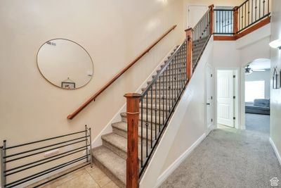 Stairs with a high ceiling, ceiling fan, and light carpet | Image 2