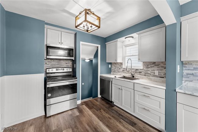 Kitchen featuring appliances with stainless steel finishes, light countertops, backsplash, a sink, and dark wood-style floors | Image 10