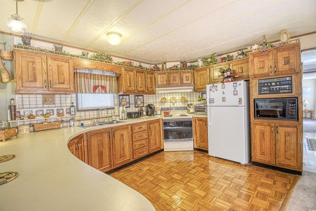 Kitchen with pendant lighting, white appliances, tasteful backsplash, sink, and light parquet floors | Image 19