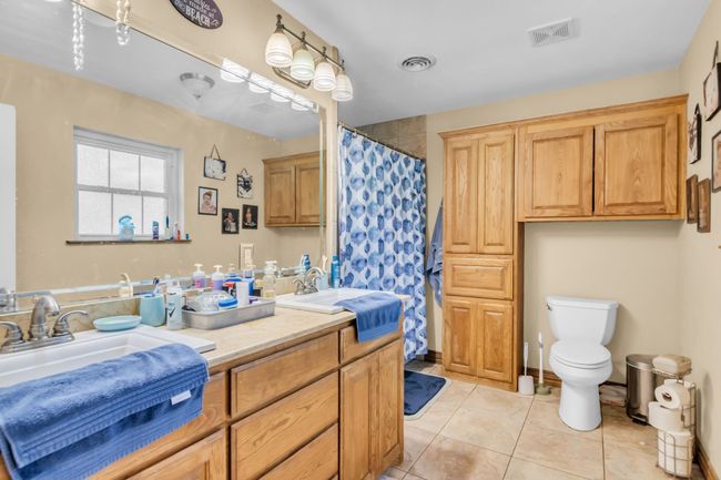 Full bath with double vanity, tile patterned floors, and a shower with shower curtain | Image 16