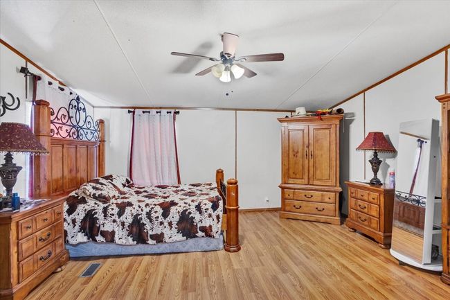 Bedroom featuring visible vents, ornamental molding, light wood-style flooring, and a ceiling fan | Image 13