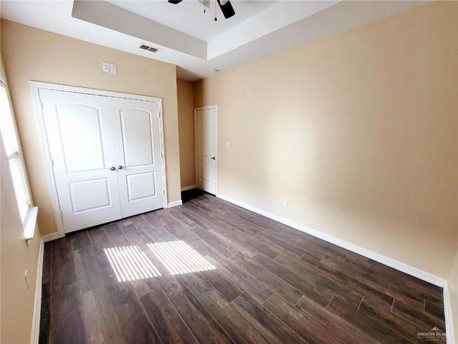 Unfurnished bedroom featuring a raised ceiling, dark wood-type flooring, and a ceiling fan | Image 13