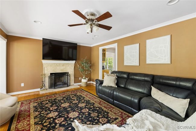 A beautiful space featuring hardwood floors, fireplace, recessed lighting, crown molding and ceiling fan | Image 6