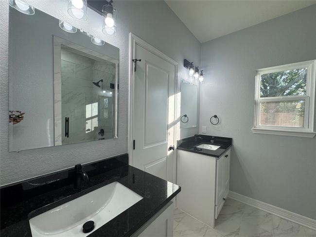 Full bathroom with a stall shower, two vanities, and marble look tiles | Image 16