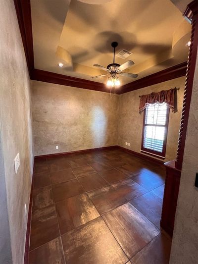 Empty room featuring ceiling fan, a tray ceiling, and ornamental molding | Image 2