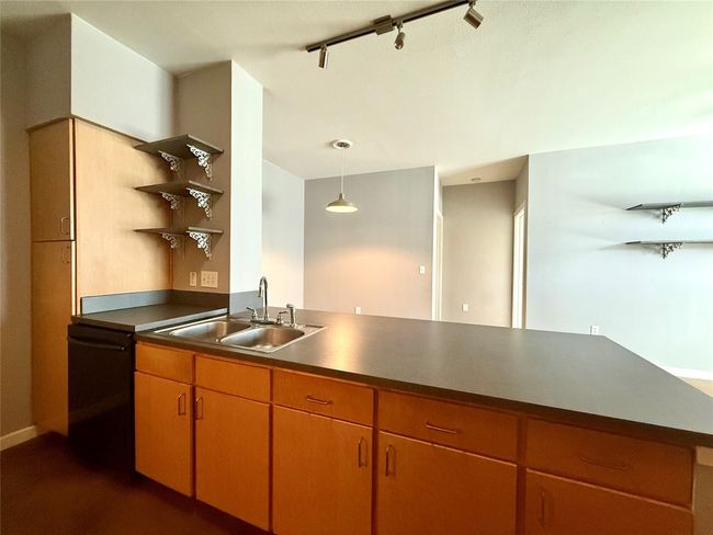 Kitchen with open shelves, a sink, black dishwasher, track lighting, and hanging light fixtures | Image 7