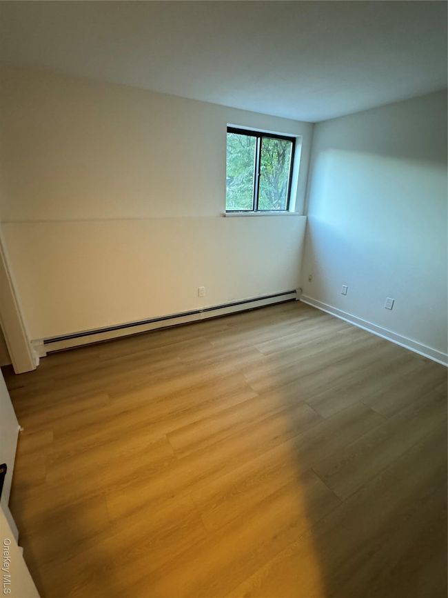 Empty room featuring a baseboard radiator and wood finished floors | Image 8