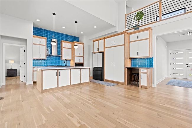 Kitchen with freestanding refrigerator, backsplash, white cabinetry, light wood-type flooring, and recessed lighting | Image 11