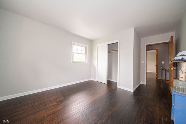 unfurnished bedroom with baseboards, dark wood-type flooring, and a closet | Image 34