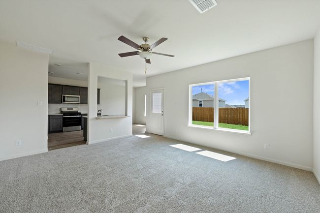 Unfurnished living room featuring light colored carpet, ceiling fan, baseboards, and a sink | Image 4