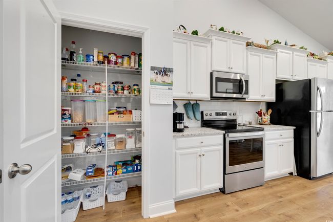 Kitchen with lofted ceiling, stainless steel appliances, light stone countertops, light hardwood / wood-style floors, and white cabinets | Image 6