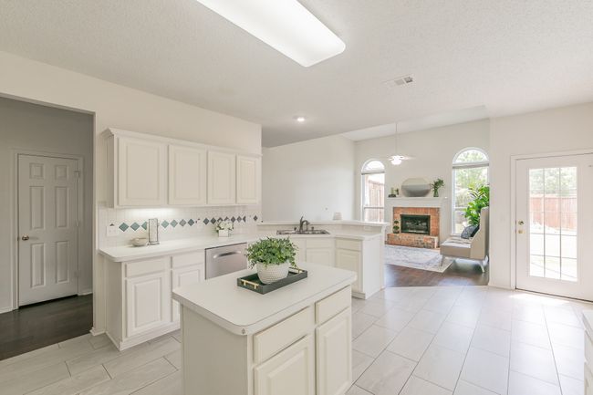 Kitchen with stainless steel dishwasher, a sink, visible vents, a brick fireplace, and light countertops | Image 34