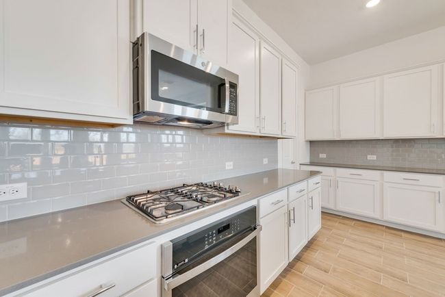 Kitchen featuring appliances with stainless steel finishes, white cabinetry, tasteful backsplash, light wood-style flooring, and recessed lighting | Image 9