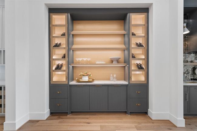 This sophisticated lounge features custom built-in cabinetry with illuminated shelving, creating a warm and inviting space perfect for displaying décor or entertaining in style. | Image 10