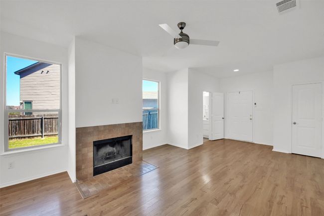 Unfurnished living room with wood finished floors, visible vents, and a healthy amount of sunlight | Image 9