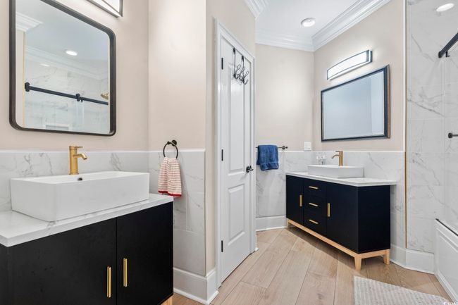 Full bath with crown molding, tile walls, two vanities, a marble finish shower, and a wainscoted wall | Image 29