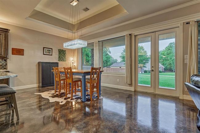 This spacious dining area easily accommodates a larger table for additional seating—perfect for hosting gatherings. Double glass doors open to the covered back porch and fire pit area, extending your entertaining space outdoors. | Image 26