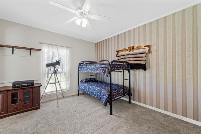 Carpeted bedroom with ceiling fan, baseboards, crown molding, and wallpapered walls | Image 22