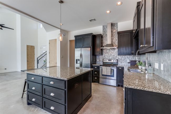 Kitchen featuring visible vents, appliances with stainless steel finishes, a kitchen island, concrete floors, and wall chimney exhaust hood | Image 8