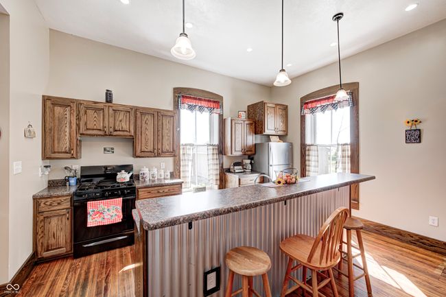 kitchen featuring dark countertops, black range with gas cooktop, freestanding refrigerator, and dark wood-style floors | Image 20