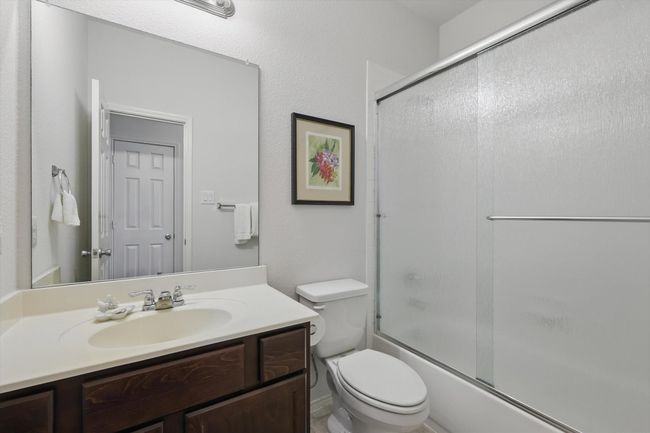 Full bathroom with toilet, vanity, and combined bath / shower with glass door | Image 11